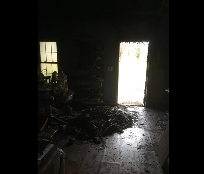 Entry way to home burnt by house fire, pile of burnt ashes on floor.
