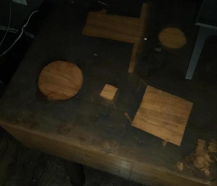 wooden desk covered in smoke soot besides the outlines of where objects had been sitting on it